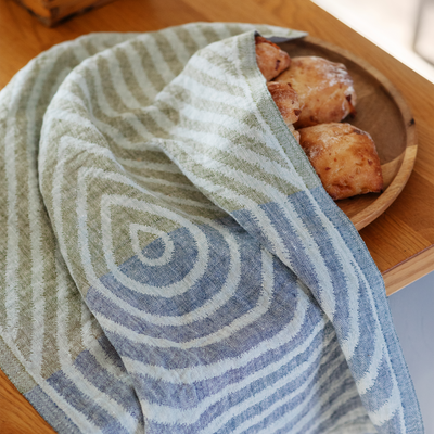 Striped towel covering a wooden plate with pastries on a wooden surface