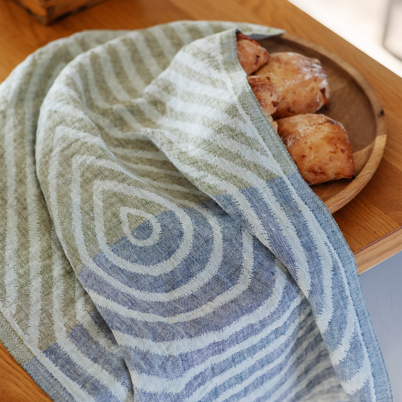 Striped towel covering a wooden plate with pastries on a wooden surface