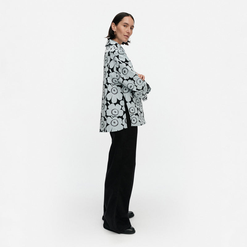 Person wearing a black and white floral patterned jacket on a white background