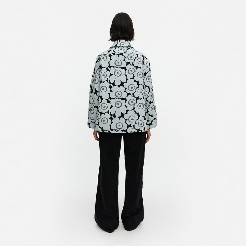Person wearing a black and white floral patterned coat on a white background