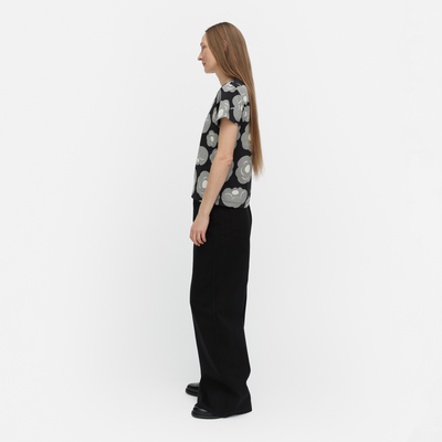 Woman wearing a black and white patterned shirt with black pants on a white background