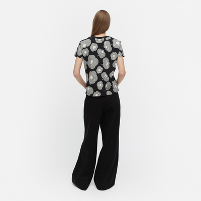 Woman wearing a black and white patterned top with black pants on a white background