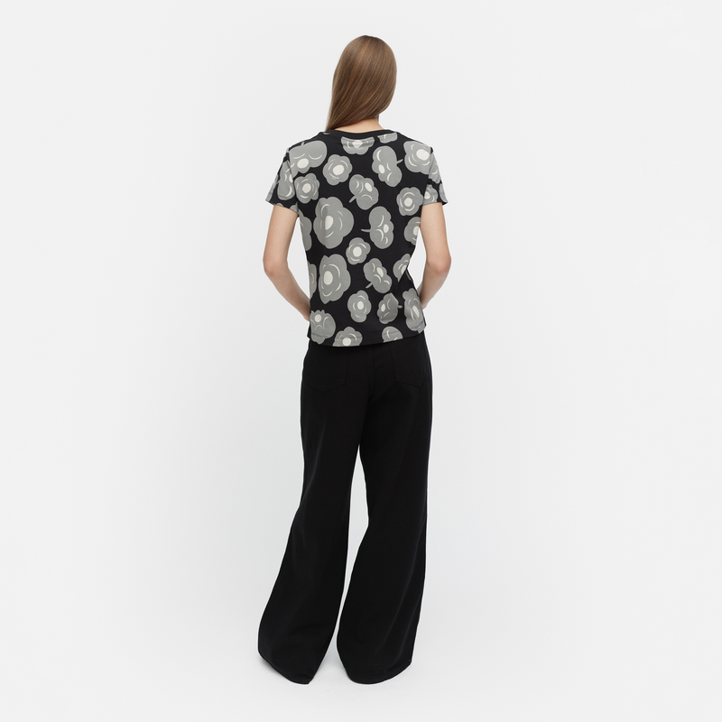Woman wearing a black and white patterned top with black pants on a white background