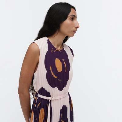 Woman wearing a sleeveless dress with purple and orange floral patterns on a white background