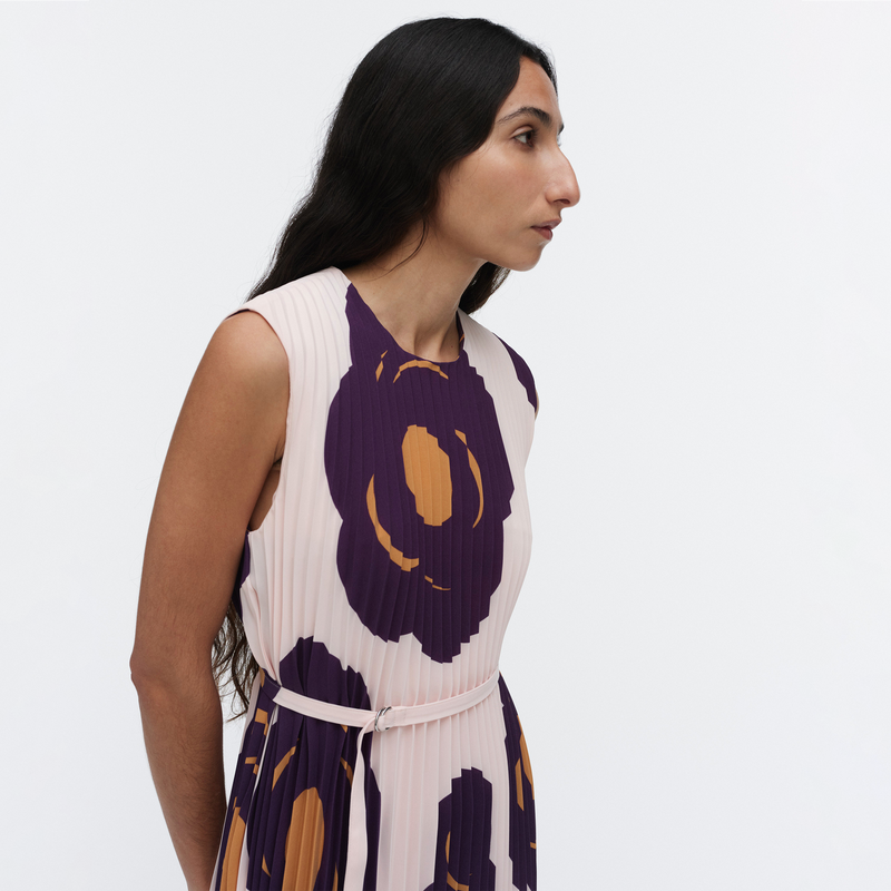 Woman wearing a sleeveless dress with purple and orange floral patterns on a white background