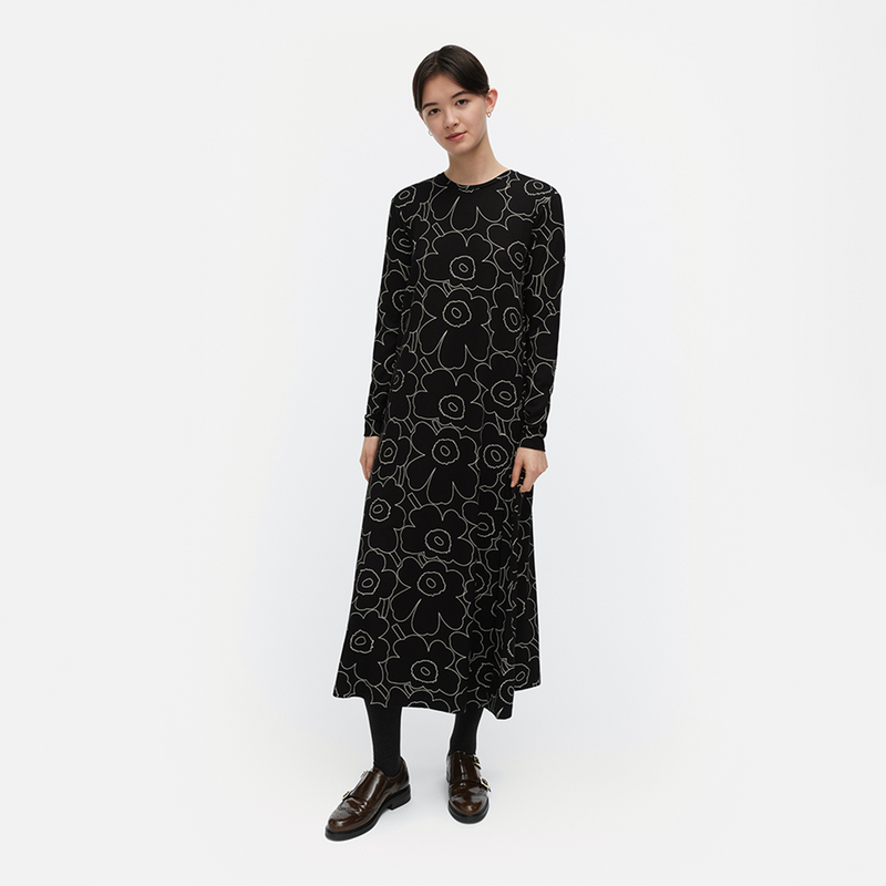 Woman wearing a black dress with white floral pattern on a white background