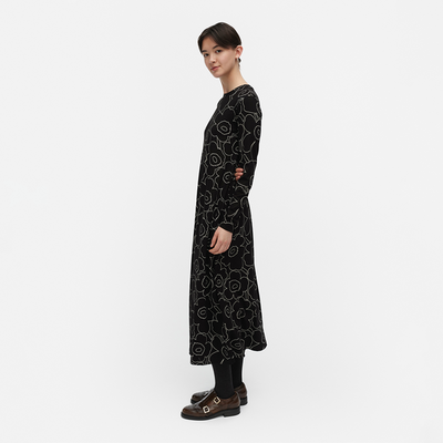 Person wearing a black patterned dress on a white background