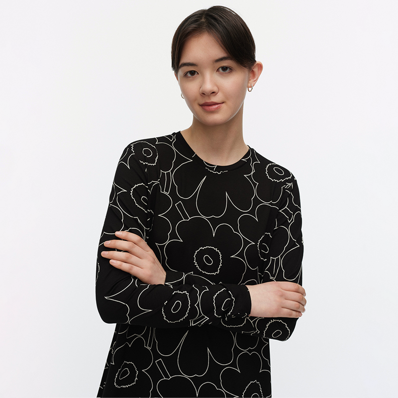Woman wearing a black dress with white floral pattern on a light gray background