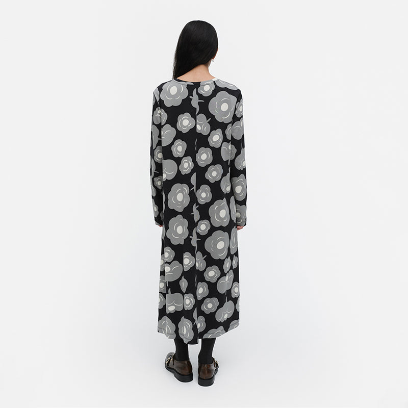 Person wearing a black floral patterned dress on a white background