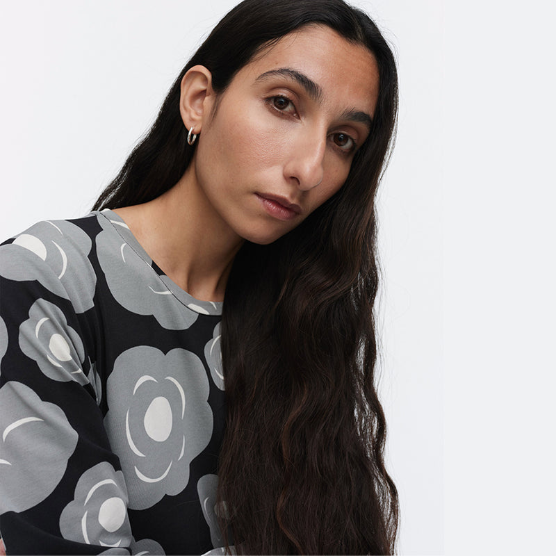 Woman wearing a black sweater with gray floral patterns on a white background