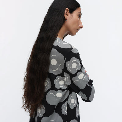 Woman wearing a black sweater with gray floral patterns on a white background