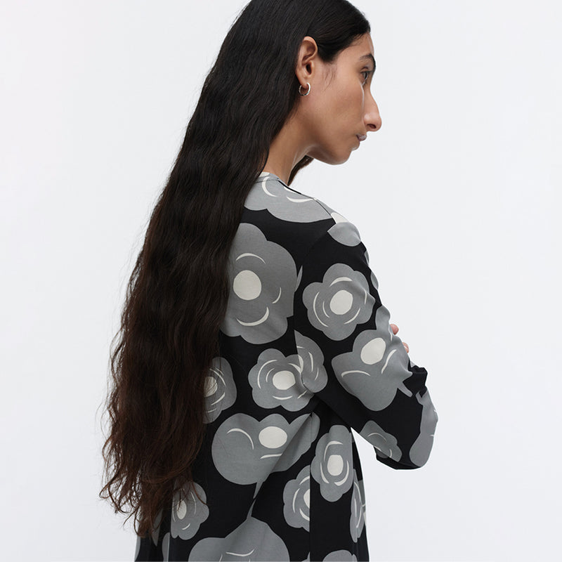Woman wearing a black sweater with gray floral patterns on a white background