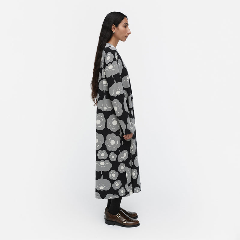 Woman wearing a long black floral coat on a white background