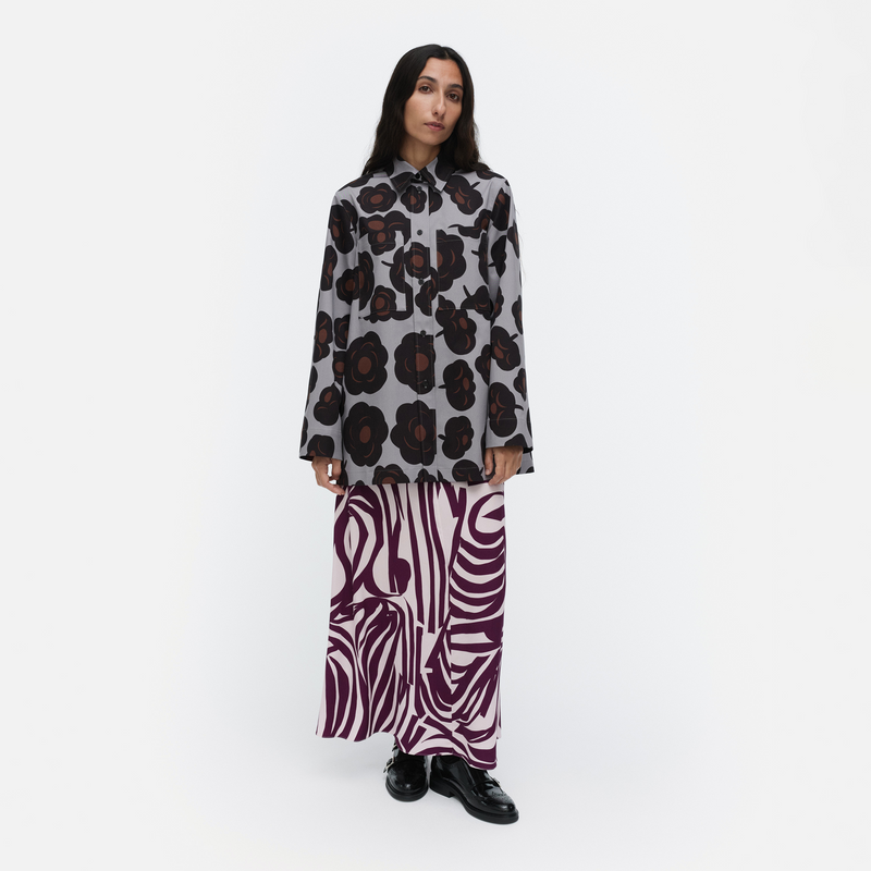 Person wearing a patterned shirt and zebra print pants on a white background