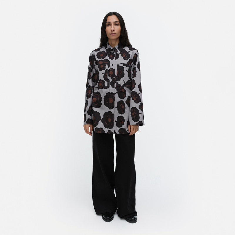 Person wearing a patterned shirt and black pants on a white background