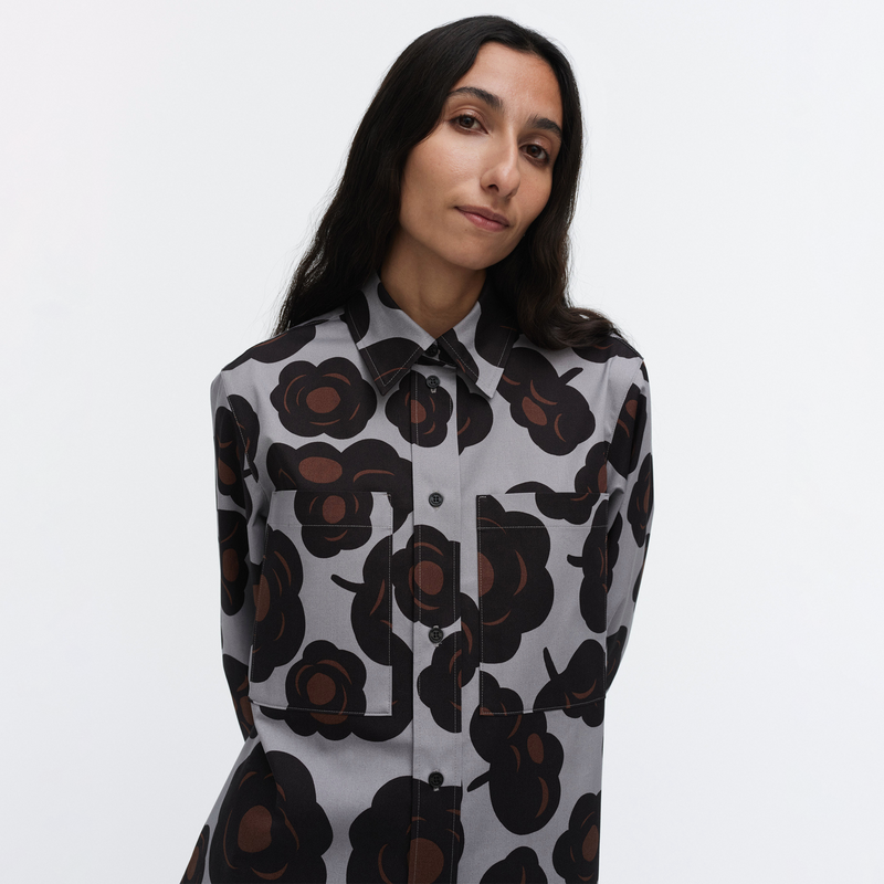 Woman wearing a patterned shirt with black and brown floral design on a white background