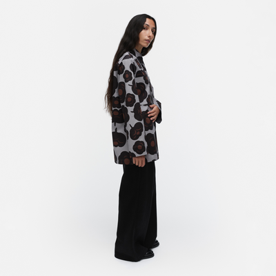 Person wearing a patterned shirt and black pants on a white background