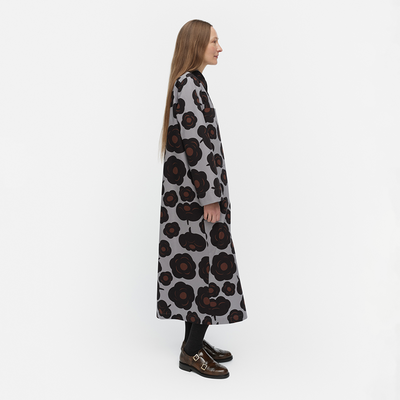 Woman wearing a long, patterned coat on a white background