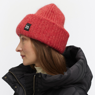 Person wearing a red knit beanie with a brand logo on a white background