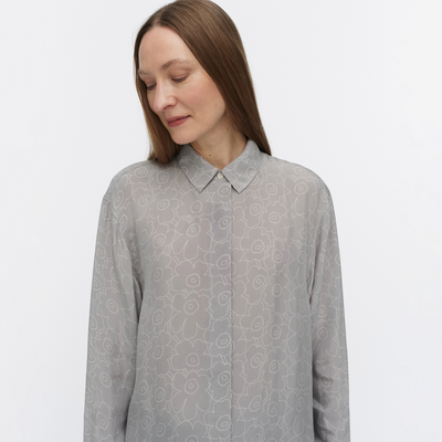 Woman wearing a gray patterned shirt against a light gray background