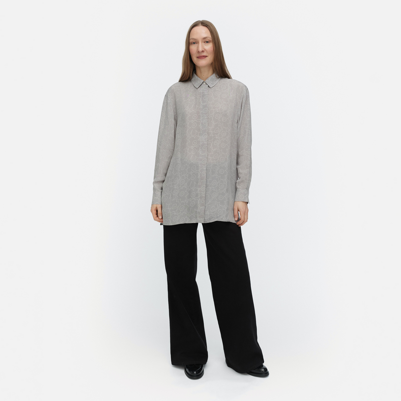 Woman wearing a gray long-sleeve shirt and black pants on a white background