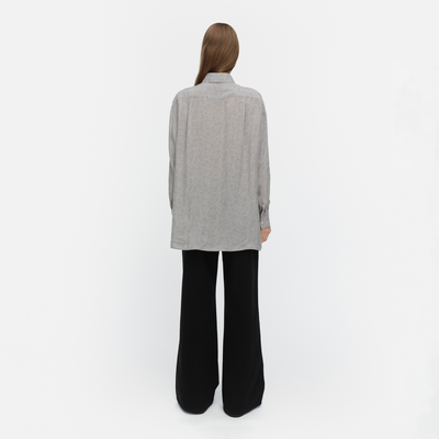 Person wearing a gray shirt and black pants on a white background