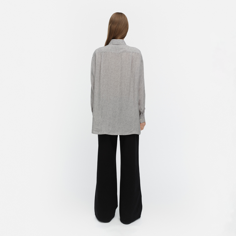 Person wearing a gray shirt and black pants on a white background