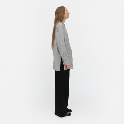 Woman wearing a gray shirt and black pants on a white background
