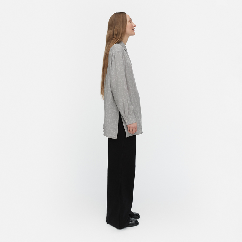 Woman wearing a gray shirt and black pants on a white background