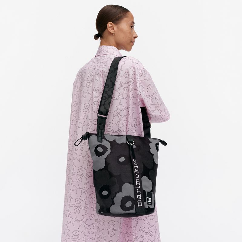 Person wearing a black floral-patterned bag with &