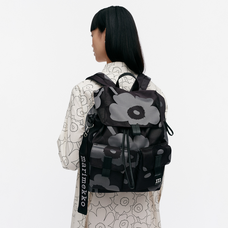 Person wearing a black floral-patterned backpack with &