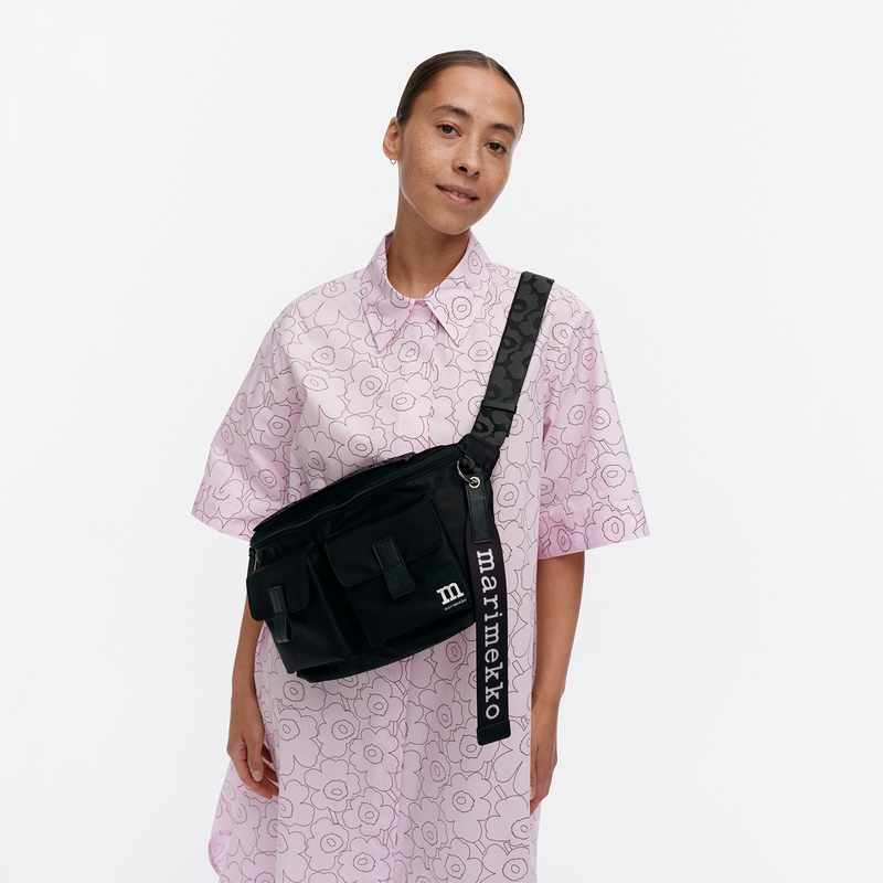 Person wearing a black Marimekko bag over one shoulder on a white background