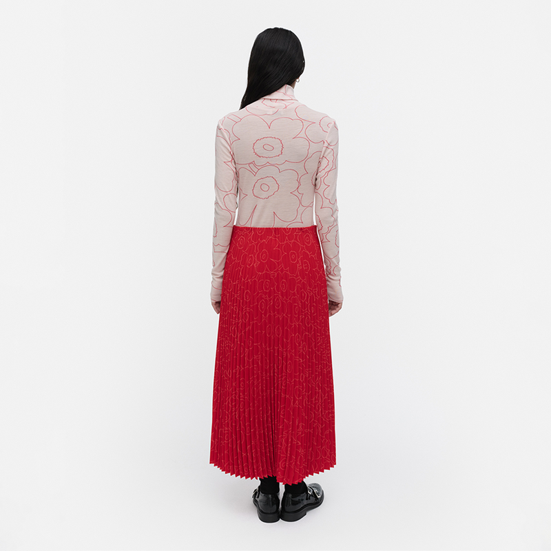 Person wearing a patterned top and red skirt on a white background