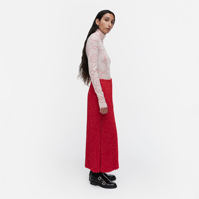 Woman wearing a red skirt and white top with floral pattern on a white background