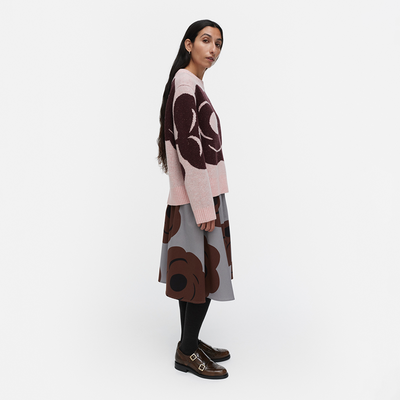 Woman wearing a patterned sweater and skirt set on a white background