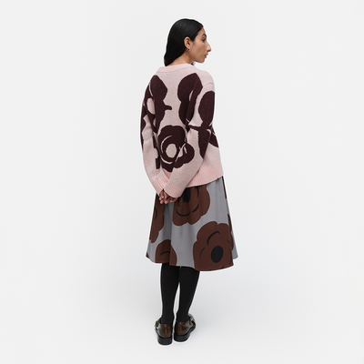 Woman wearing a patterned sweater and skirt set on a white background