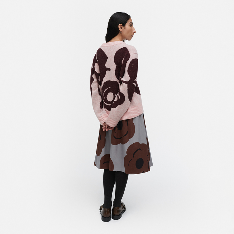 Woman wearing a patterned sweater and skirt set on a white background