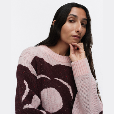 Woman wearing a pink and brown patterned sweater on a white background