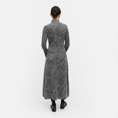 Person wearing a long gray dress with floral pattern on a white background