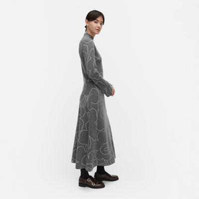 Woman wearing a long gray dress with white patterns on a white background