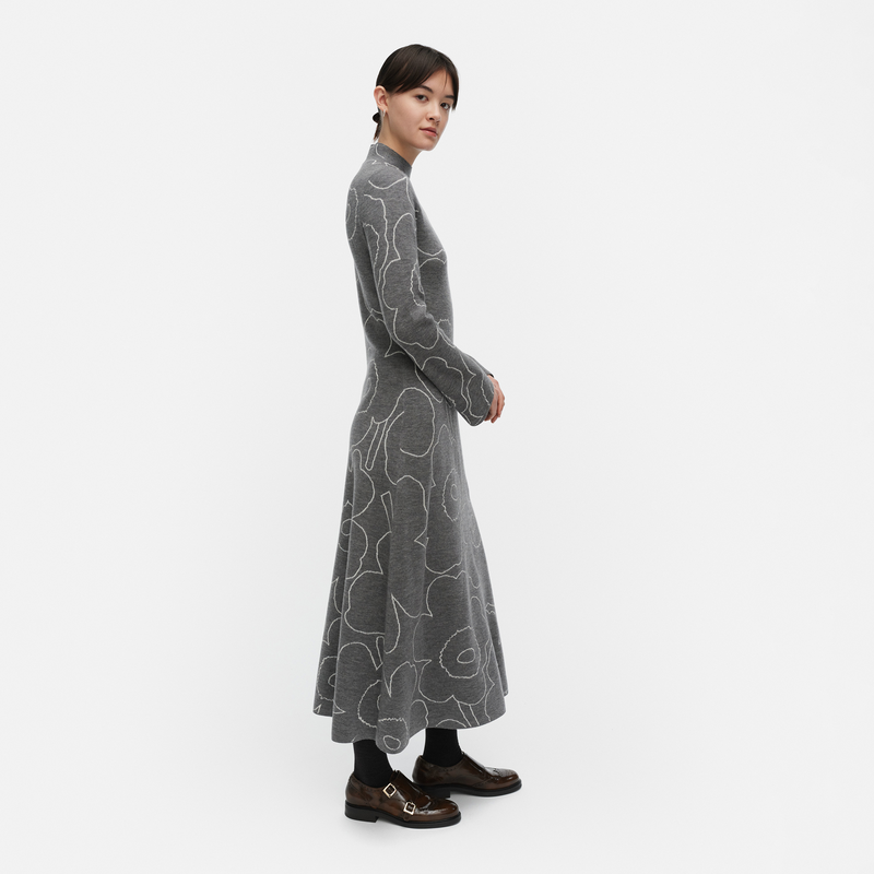 Woman wearing a long gray dress with white patterns on a white background