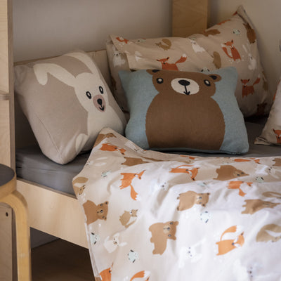 Children's room with animal-themed pillows and blanket on a bed.