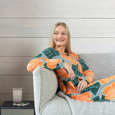 Woman sitting on a couch wearing a colorful kimono-style garment with a wooden wall background
