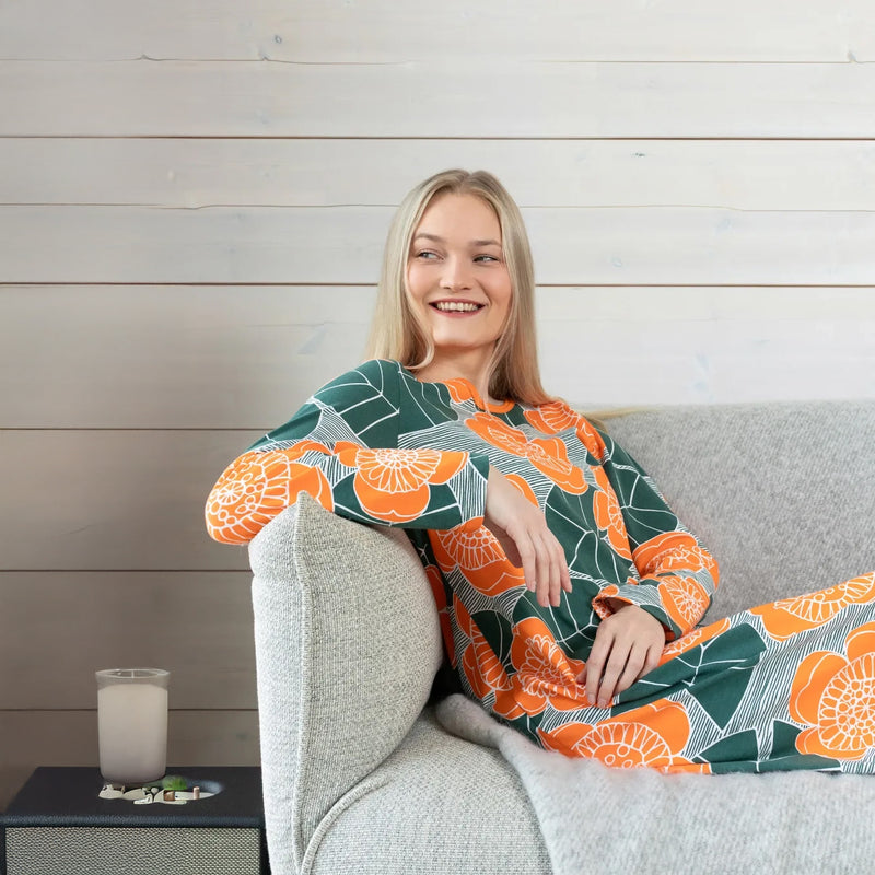 Woman sitting on a couch wearing a colorful kimono-style garment with a wooden wall background
