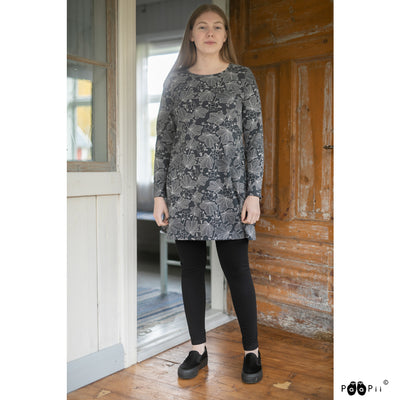 Woman in black pants and shoes wearing Kannel cloudberry tunic in shadow