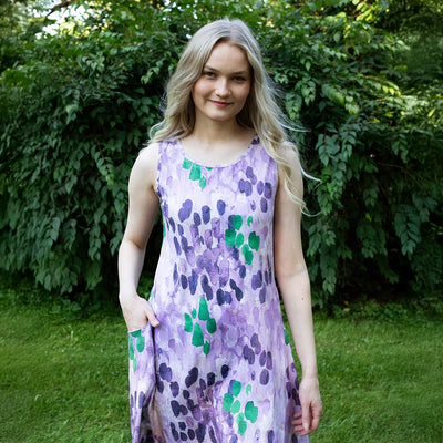 Woman wearing a purple floral dress standing in a garden