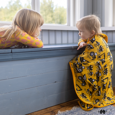 sister with brother snuggled in machines baby blanket