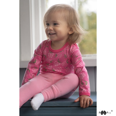 Smiling toddler wearing long-sleeved pink onesie