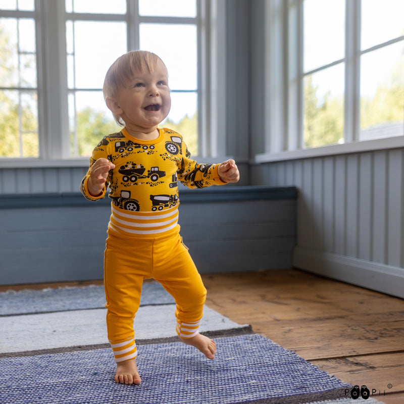 Playful baby wearing yellow Finnish onesie