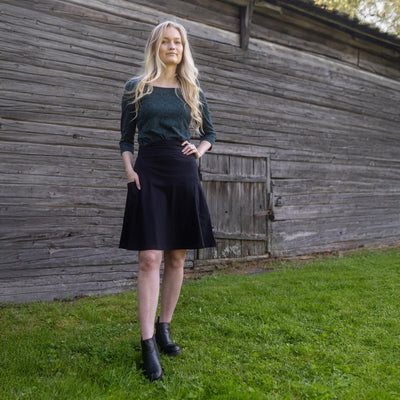 Woman standing in front of a wooden building on grass